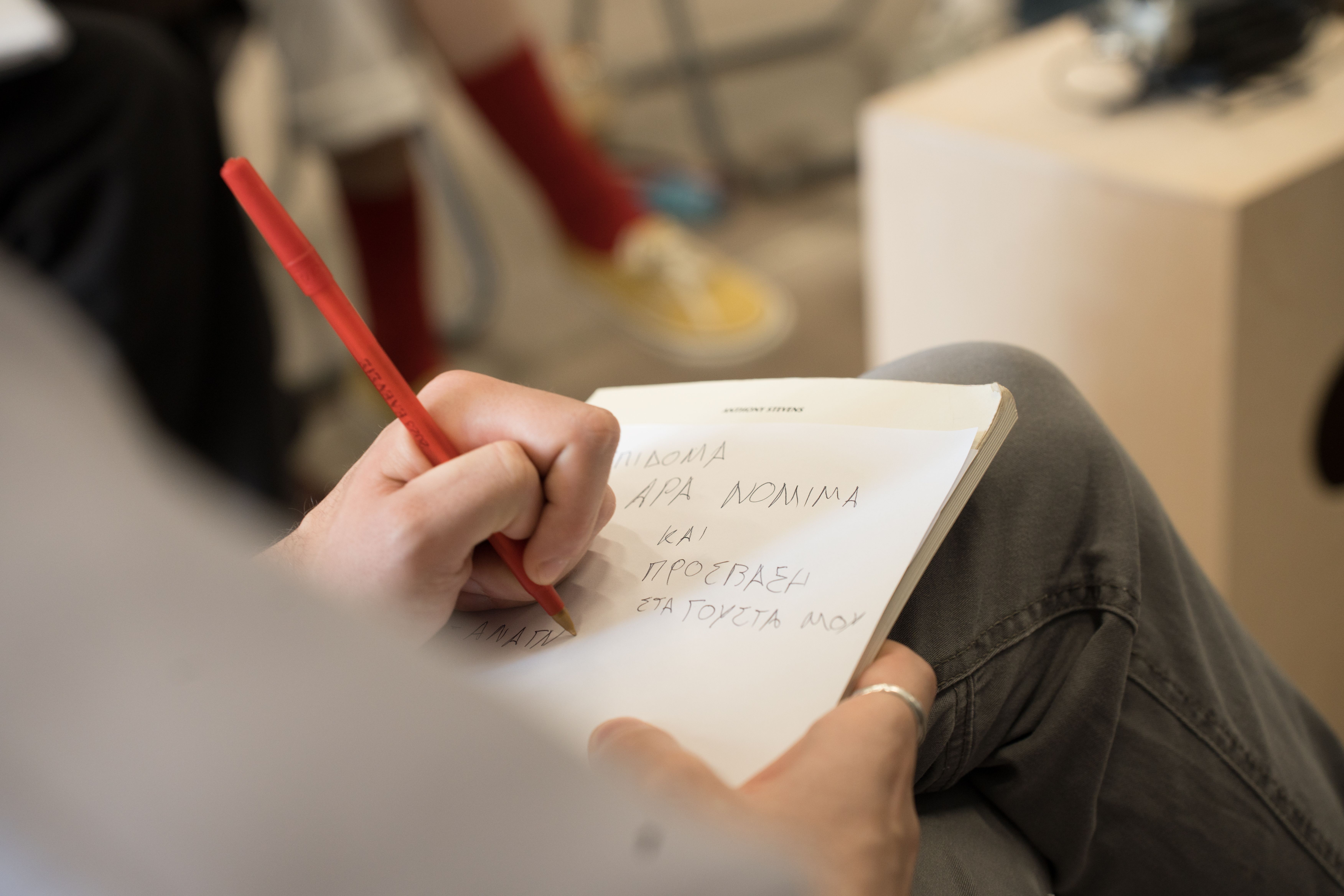 A photo focusing on a notebook lying open on someone's lap as they write in pencil, in capital letters: 'And access to my tastes.'